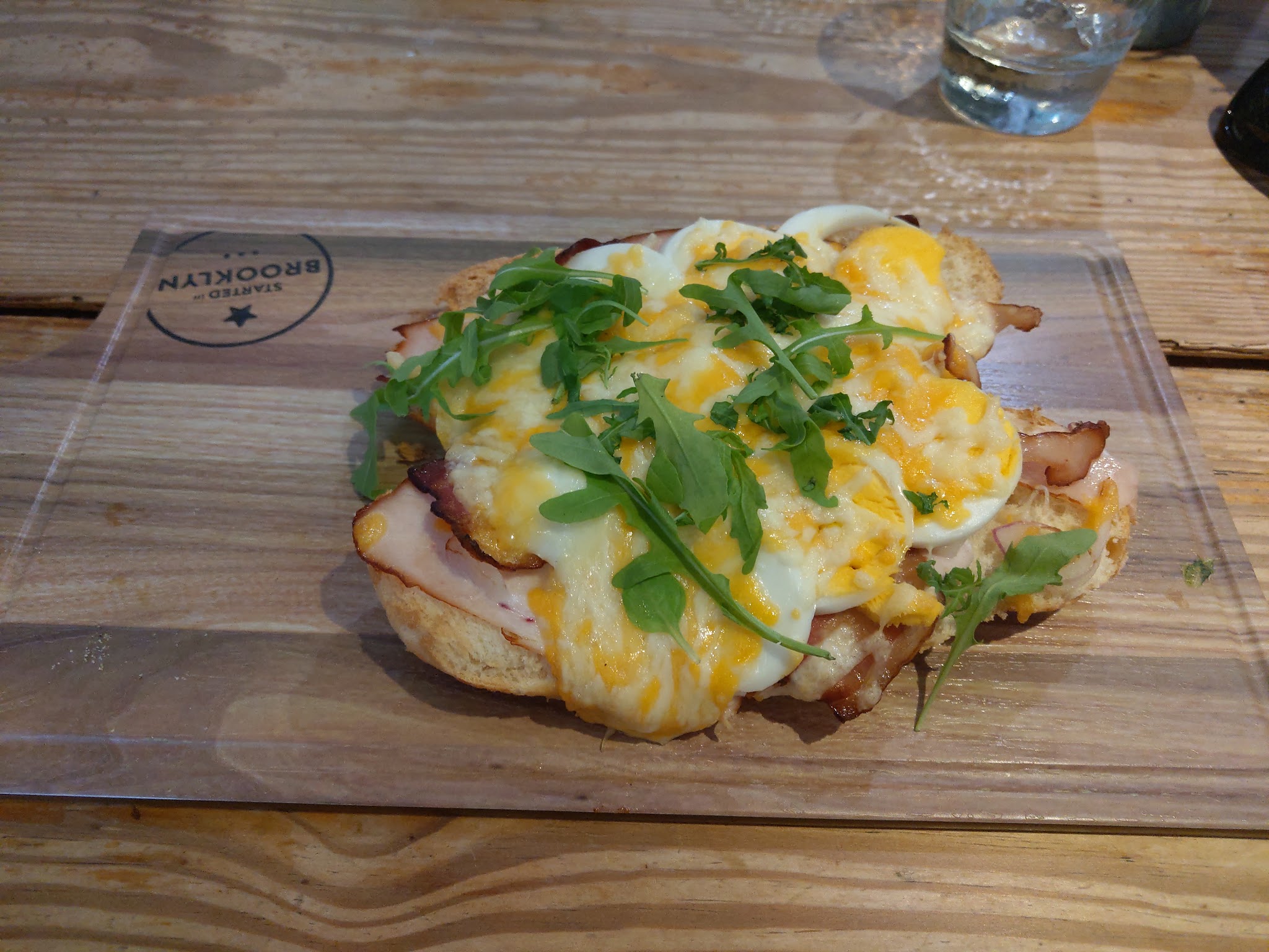 Een lunchgerecht met ei en groen op een houten serveerplank